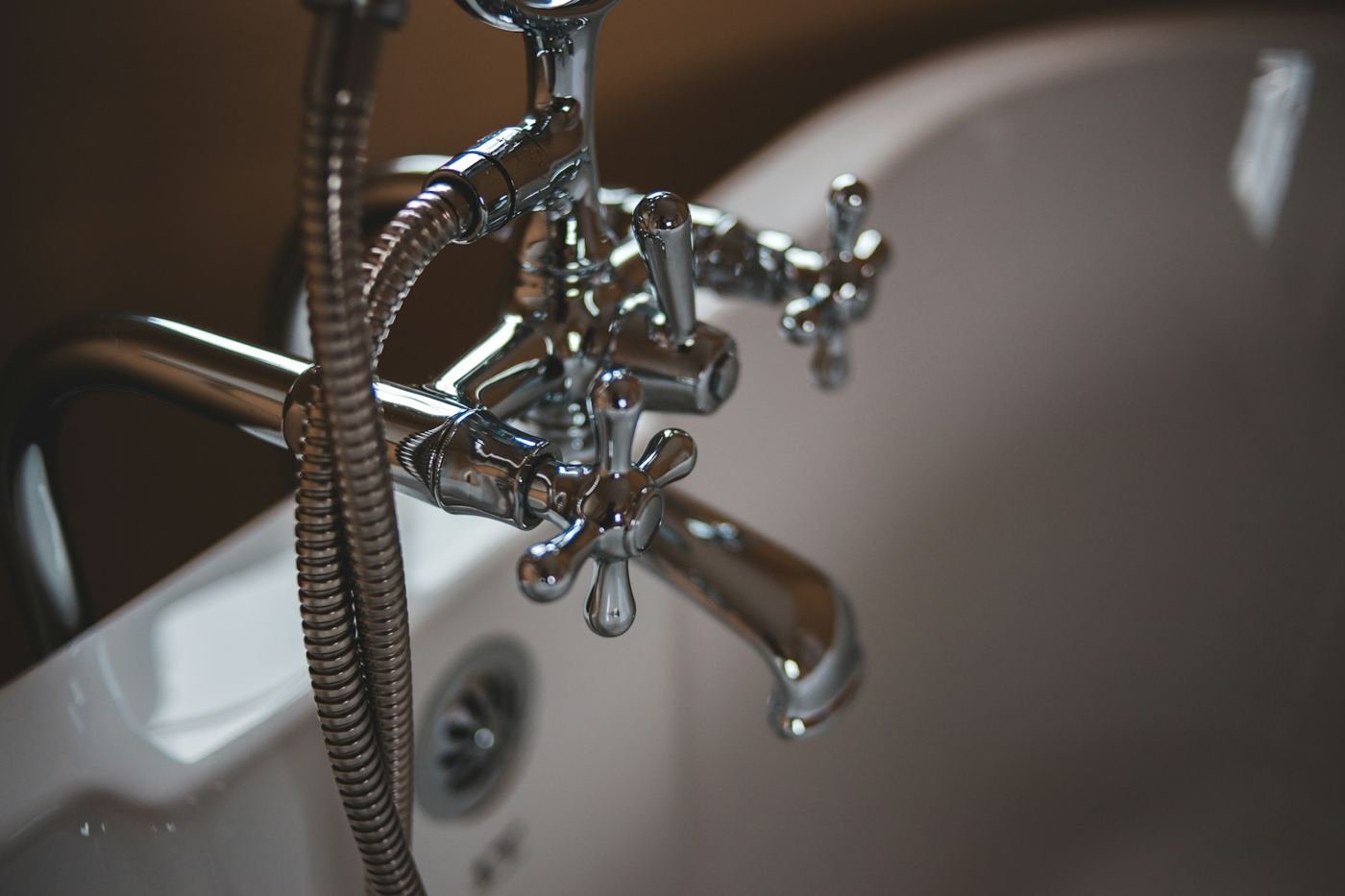 Chrome bath faucet and hand shower, the kind of fixture that starts dripping