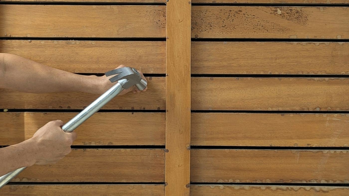 Hammering a cedar fence board into place