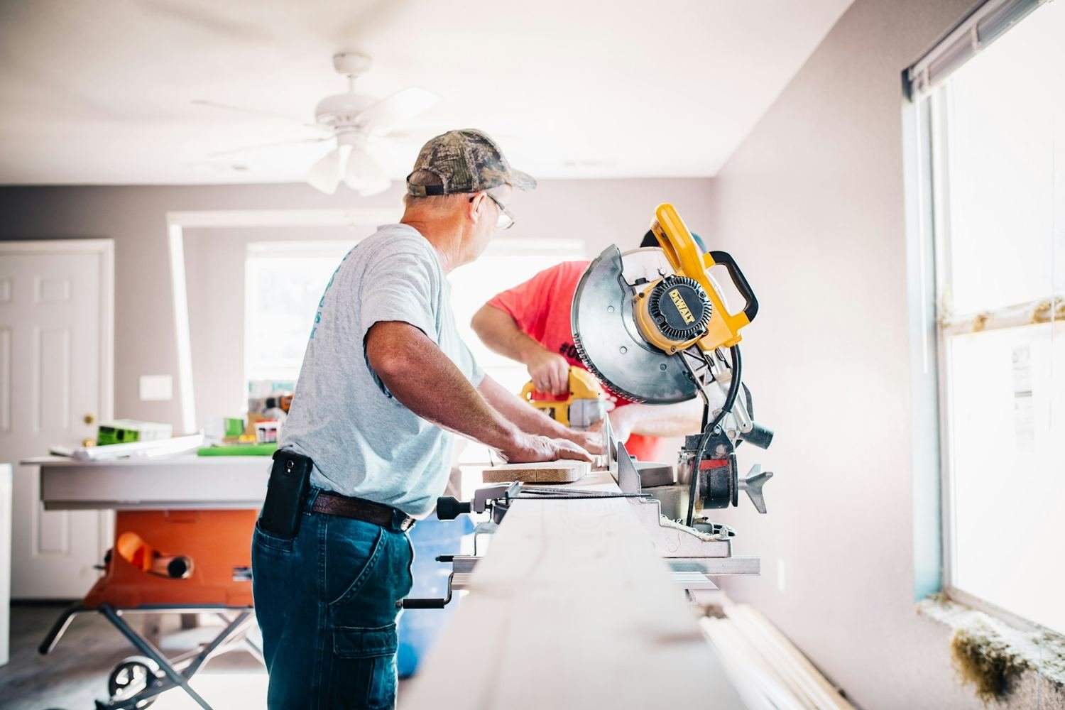 Craftsman cutting trim on a miter saw inside a home being renovated