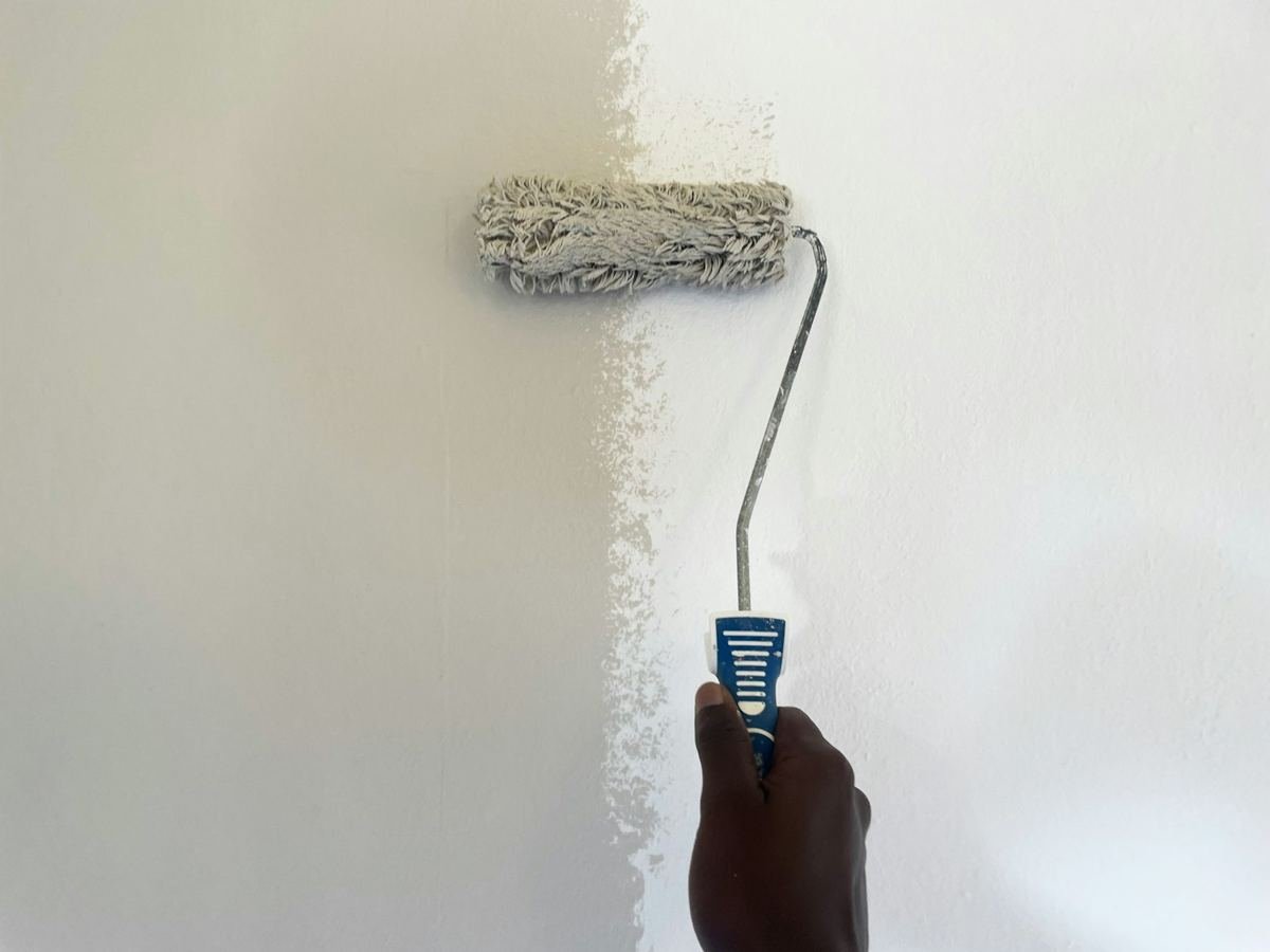 Paint roller laying fresh white paint onto a wall